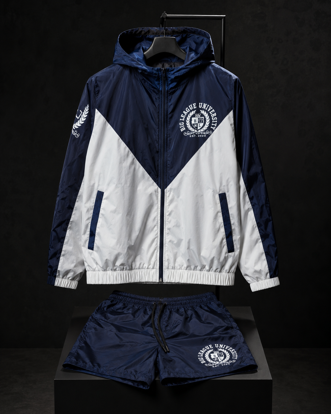 Navy and white Big League University windbreaker set on a dark pedestal display.