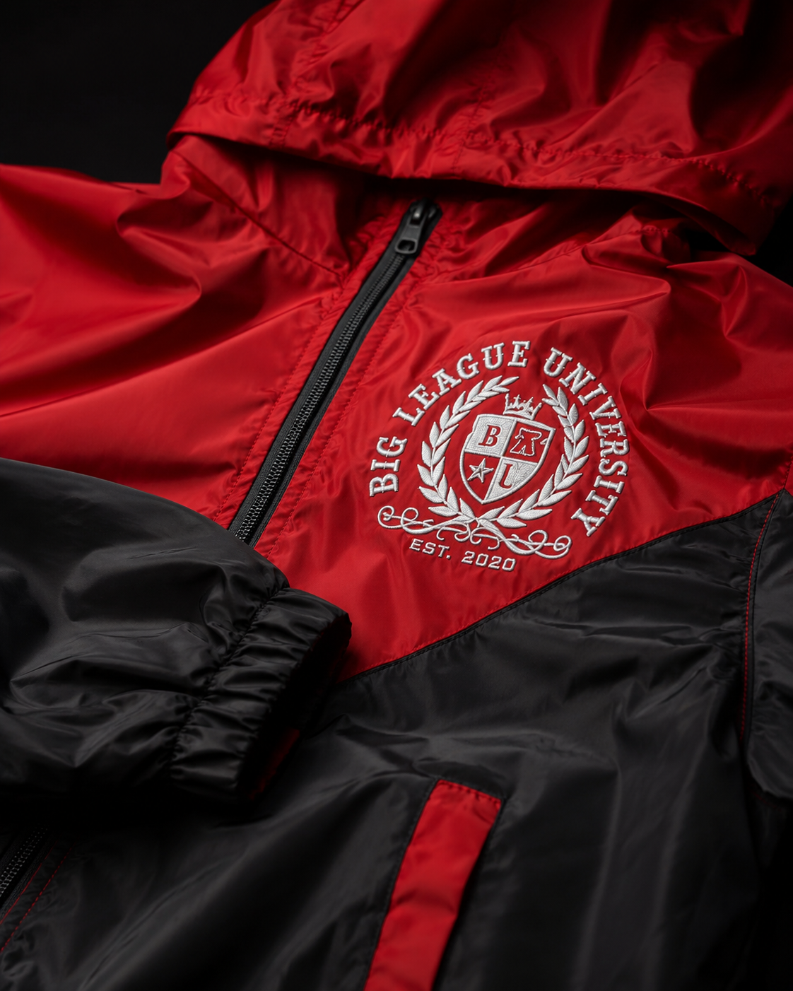 Close-up detail of the red and black Big League University windbreaker crest and technical fabric.